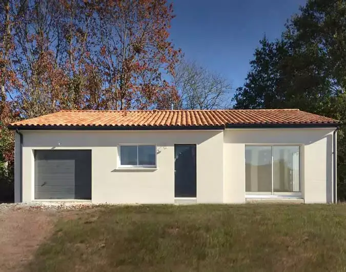 Maison de plain-pied avec toit en tuiles rouges, façade beige, garage intégré et grande baie vitrée, entourée d'arbres, sous un ciel dégagé.