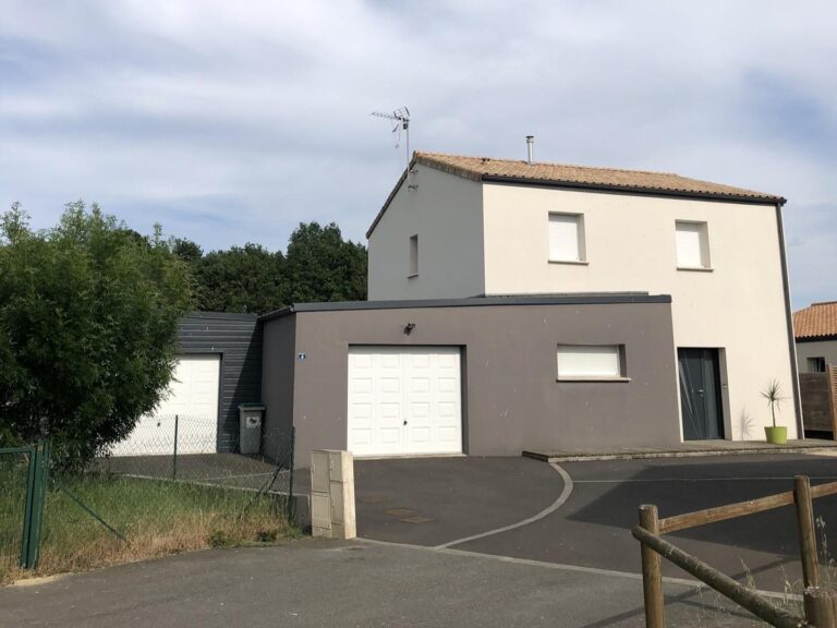 Maison avant travaux, avec une façade blanche simple et un toit en tuiles rouges. Le jardin offre une pelouse bien entretenue et une terrasse en bois, créant un espace extérieur convivial en attente d'une modernisation et d'une extension pour optimiser le style et la fonctionnalité.