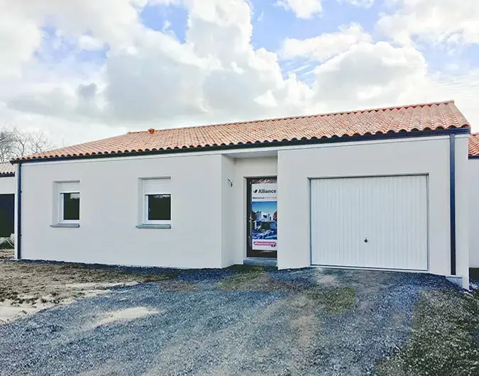 Façade de maison contemporaine de plain-pied avec toit en tuiles rouges, crépi blanc, garage intégré et allée en gravier.