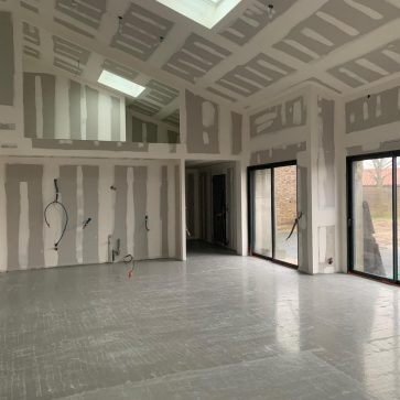 Vue intérieure d'un chantier en rénovation, avec les murs en placo en cours de finition et une chape sèche prête à recevoir le revêtement de sol.