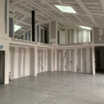 Vue intérieure d'un espace en cours de rénovation, avec cloisons en placo et pré-installations électriques et sanitaires, prêt pour les finitions dans un projet de transformation architecturale moderne.