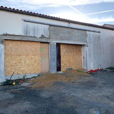 Ouverture d'un mur pour la création d'un garage, avec murs en béton et fondation en cours