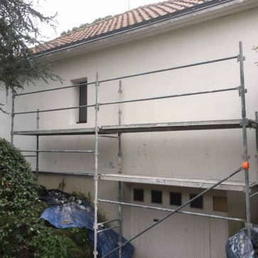 Rénovation de façade en cours avec échafaudage installé, préparations des murs pour l'application d'un enduit extérieur de finition. Maison individuelle avec toiture rénovée.